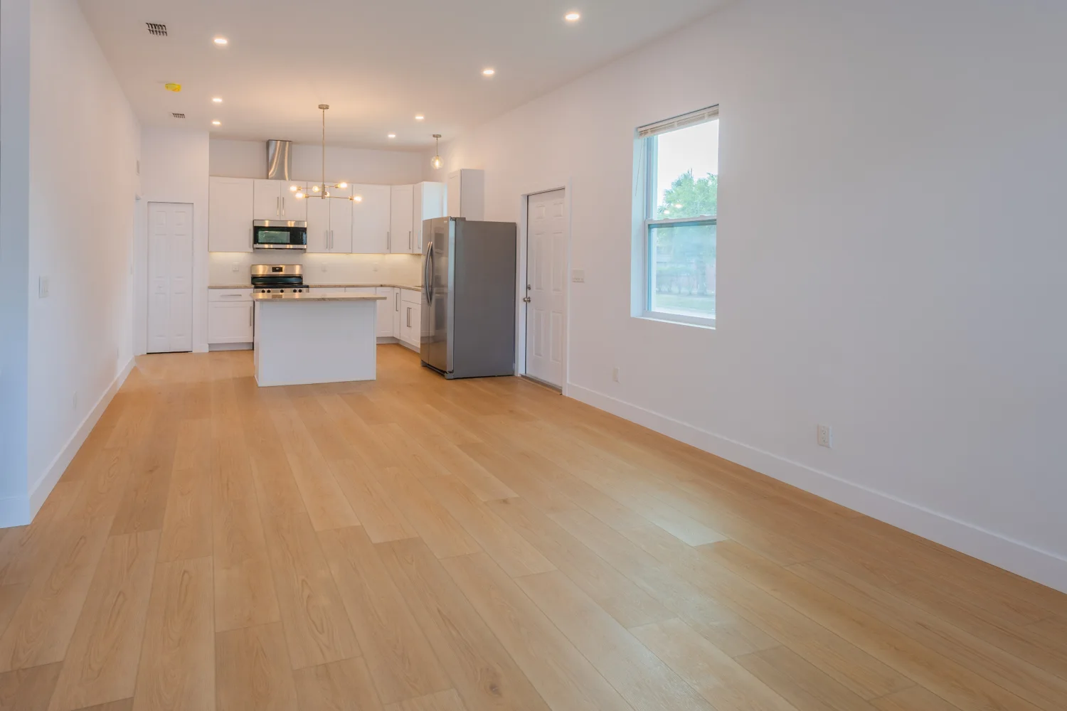 Open living area leading to a white kitchen